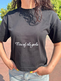 T-shirt streetwear nera con scritta 'Fire of the gods', indossata da donna all'aperto