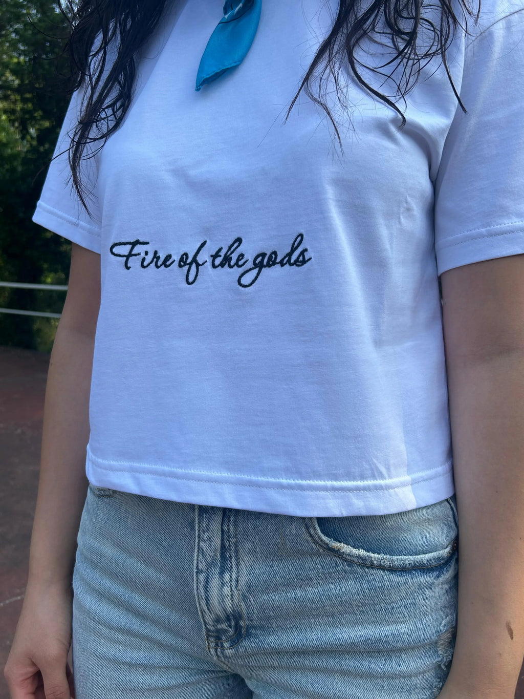 Maglietta streetwear bianca con scritta nera "Fire of the gods" e jeans chiari da donna