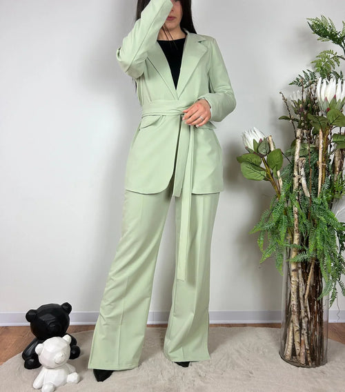 Donna con completo elegante verde chiaro stile streetwear, pantaloni e giacca con cintura, moda casual.